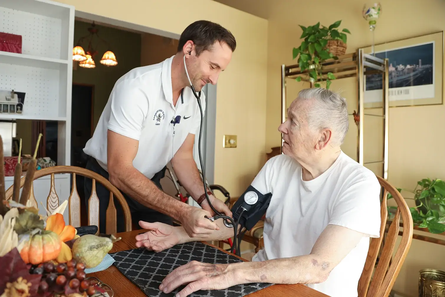 VNA Employee checking patient's blood pressure at kitchen table