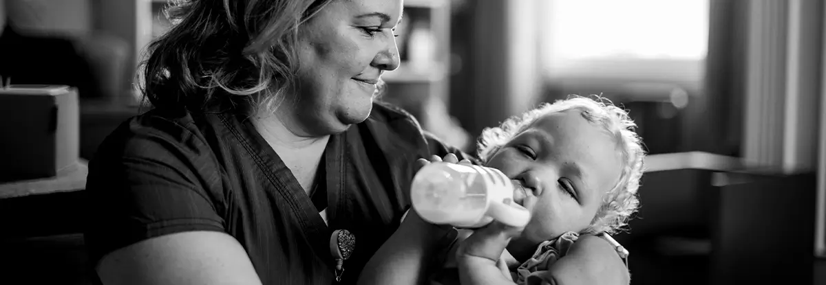 VNA nurse holding baby in arms feeding a bottle